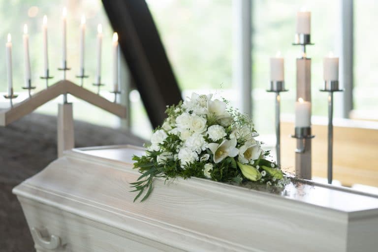 Liten båredekorasjon med hvite liljer og roser på hvit kiste