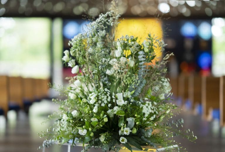 Stor blomsterdekorasjon med hvite blomster og grønne blader