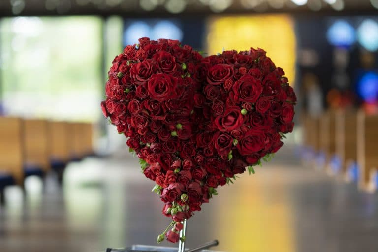 Hjerteformet blomsterdekorasjon med røde roser til begravelse