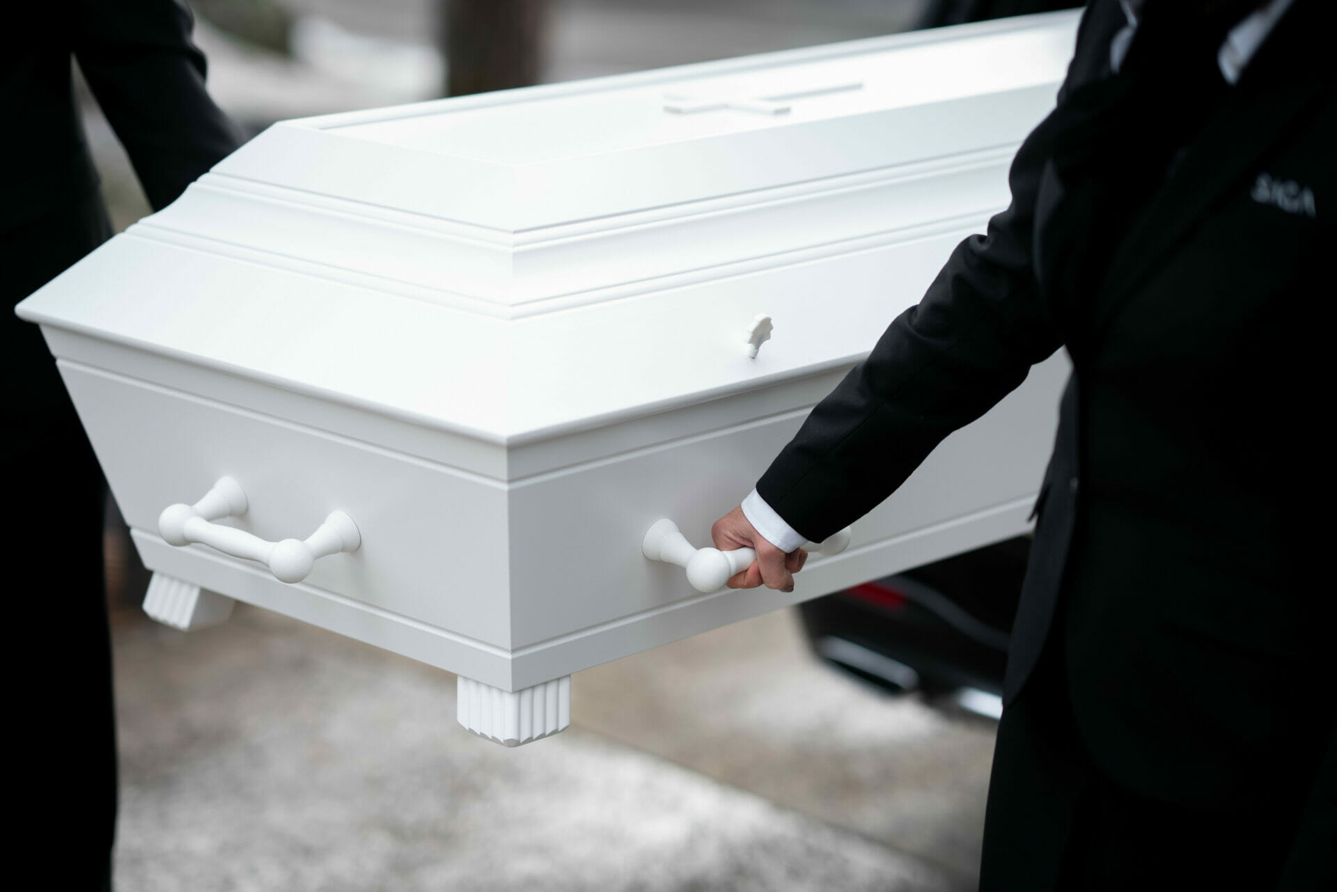 Begravelsesagenter fra Saga Begravelsesbyrå bærer hvit gravkiste i begravelse